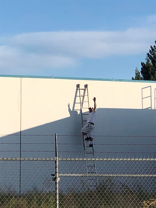 Bayshore Painters employee painting the exterior of a commercial building in El Dorado Hills, CA